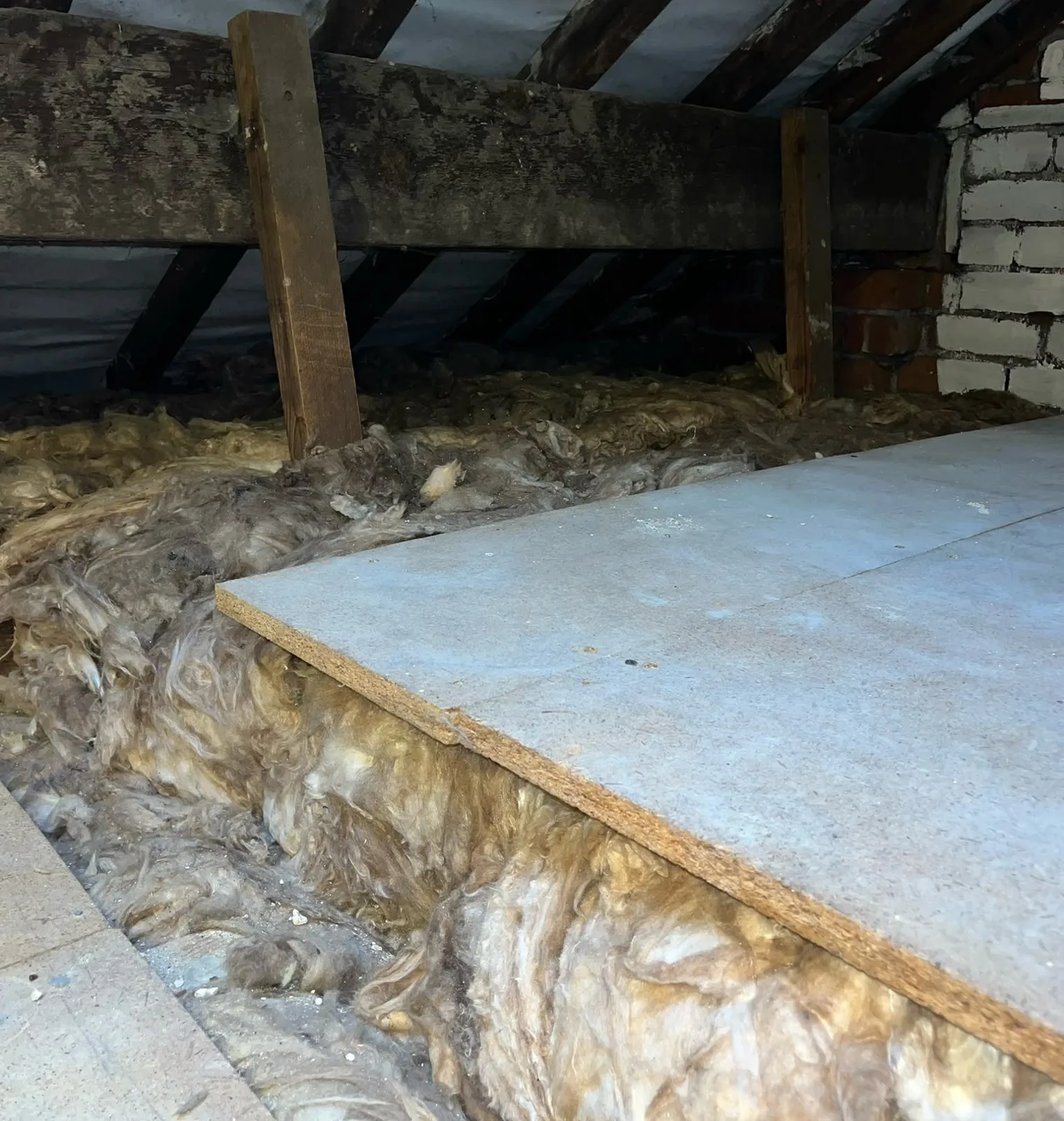 Edge of raised loft boarding in Kendal showing mineral wool insulation running underneath