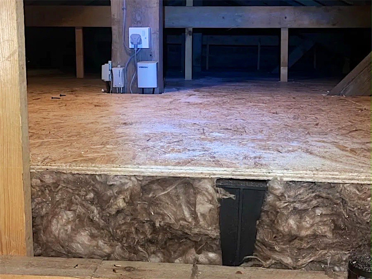 A raised loft boarding platform on loft legs, with full-depth insulation left uncompressed underneath