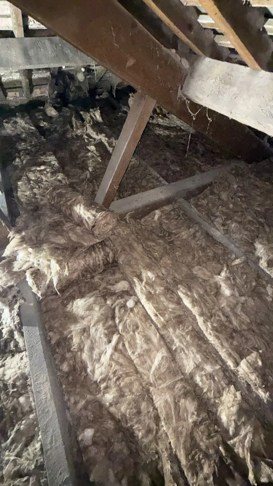 Second layer of mineral wool loft insulation rolled across the joists in a Macclesfield loft