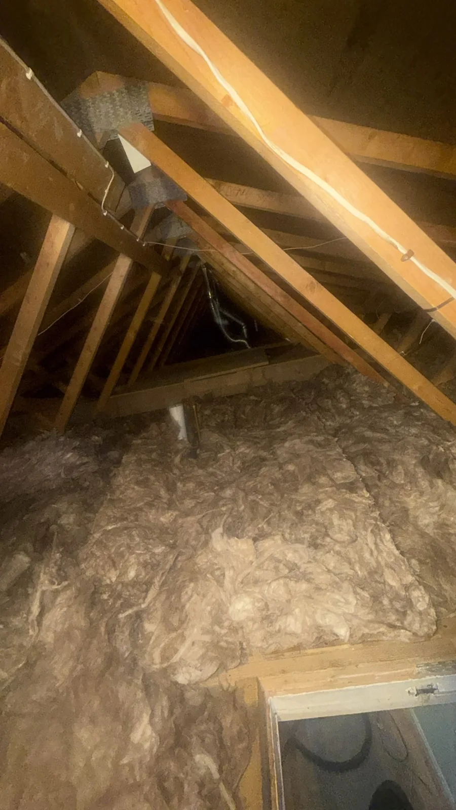 New 300mm mineral wool loft insulation laid across the joists beside the hatch in a Rhyl loft