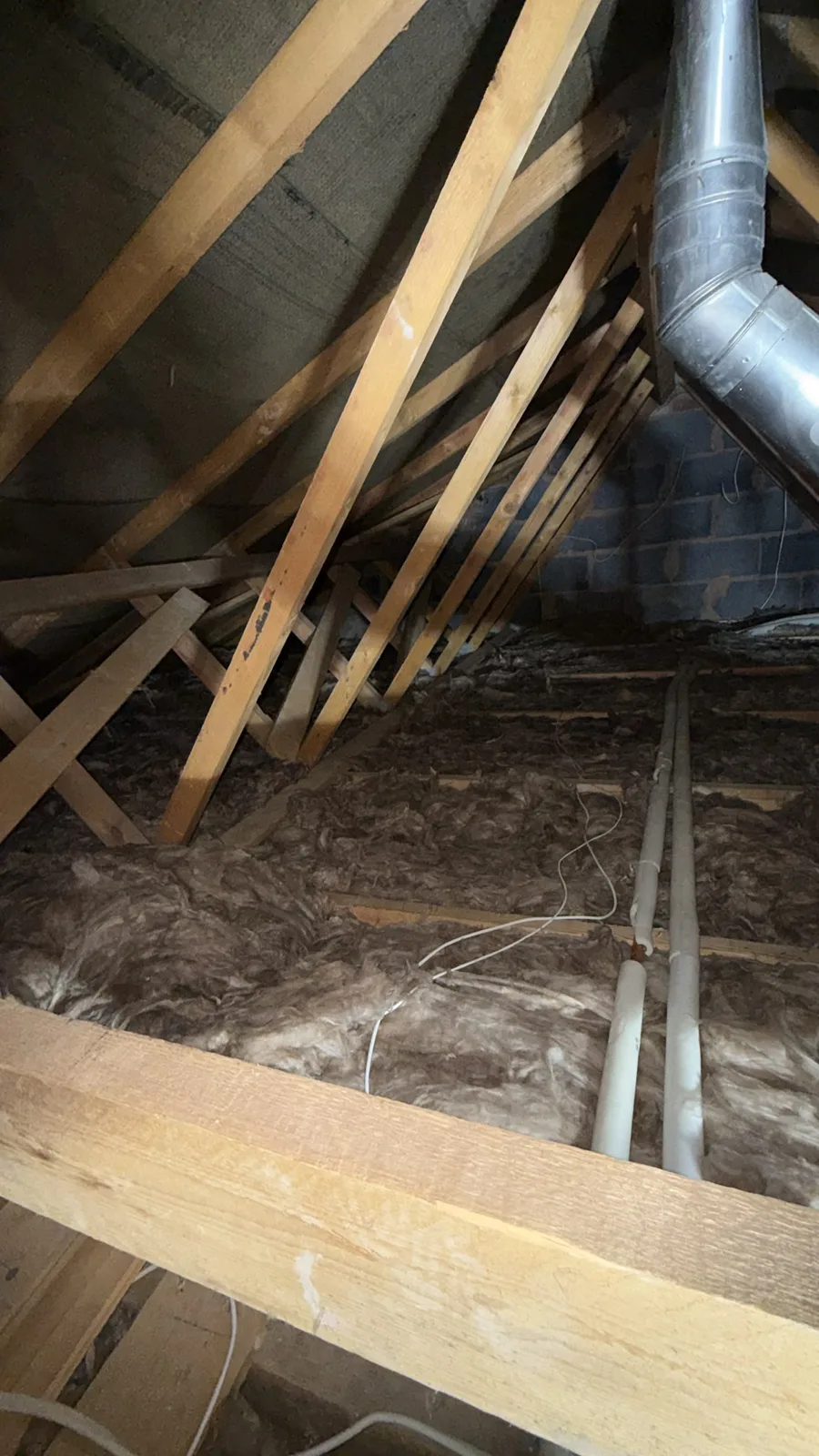 Thin, worn loft insulation between the joists in a Rhyl loft before it was stripped out