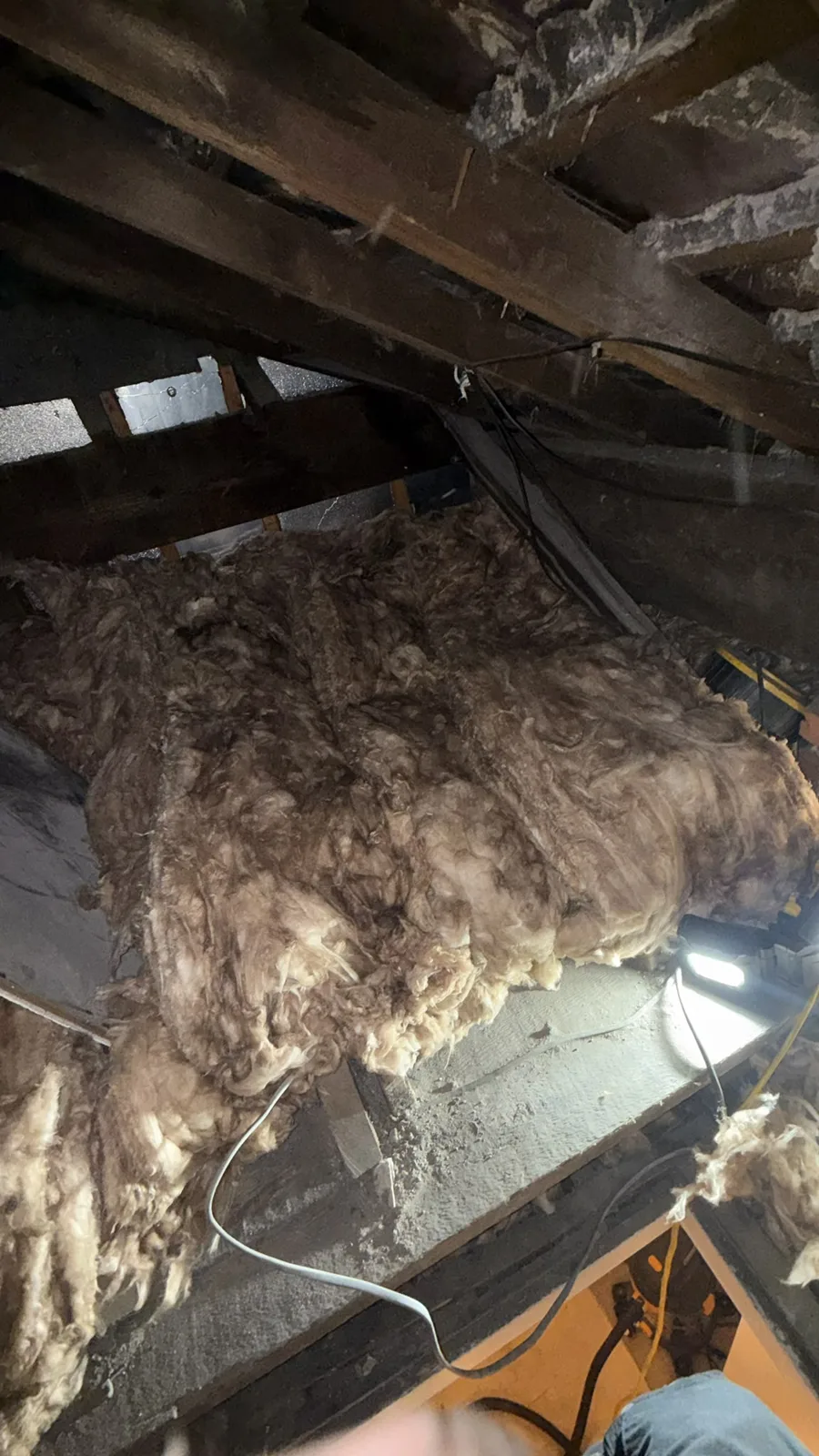 Old insulation lifted from the joists during loft insulation removal in Salford