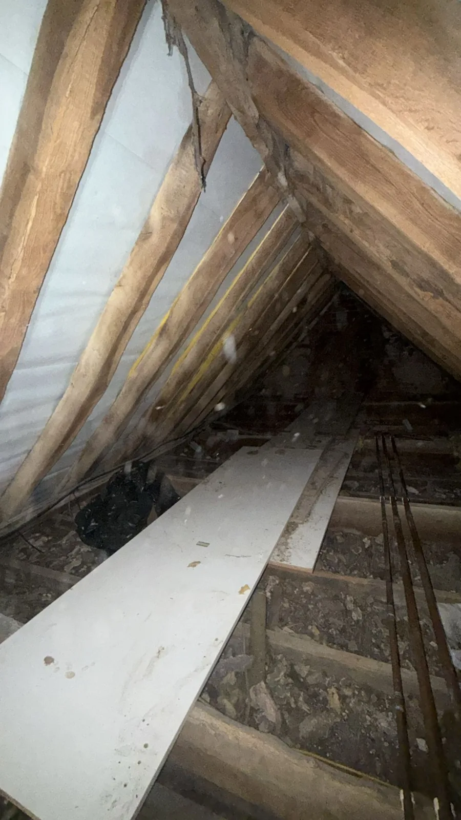 Sleaford area loft before new loft insulation, with old boards and debris across the joists