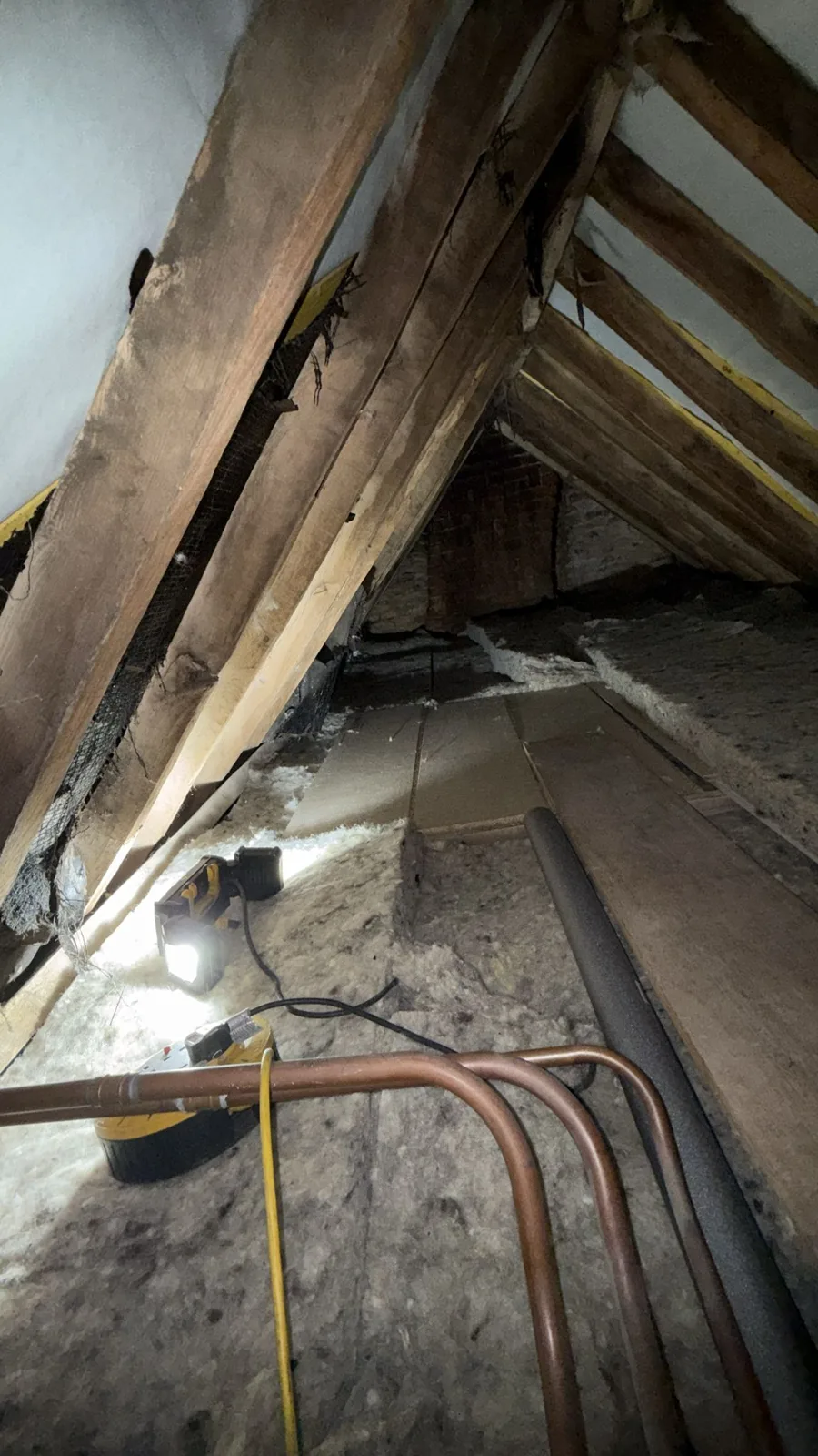 Loft pipework being lagged during loft insulation work near Sleaford