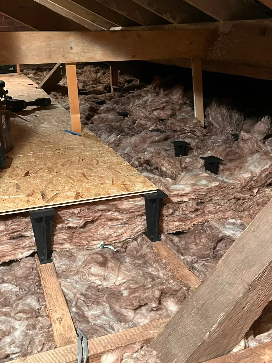 Raised loft legs set through new mineral wool with OSB boards being laid across them