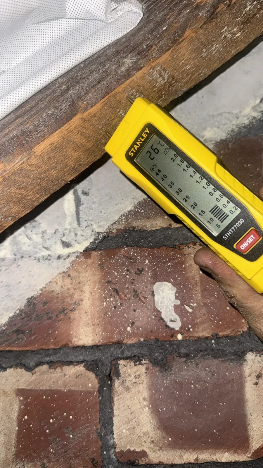 Moisture meter on a roof timber during spray foam removal in Oldham